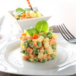 Russian salad with peas, carrots, potatoes and mayonnaise on complex background