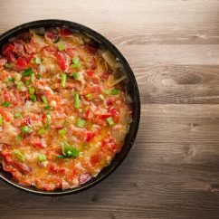 Stewed tomatoes with onions in a plate on a wooden background. stewed tomatoes with onion top view. vegetarian food
